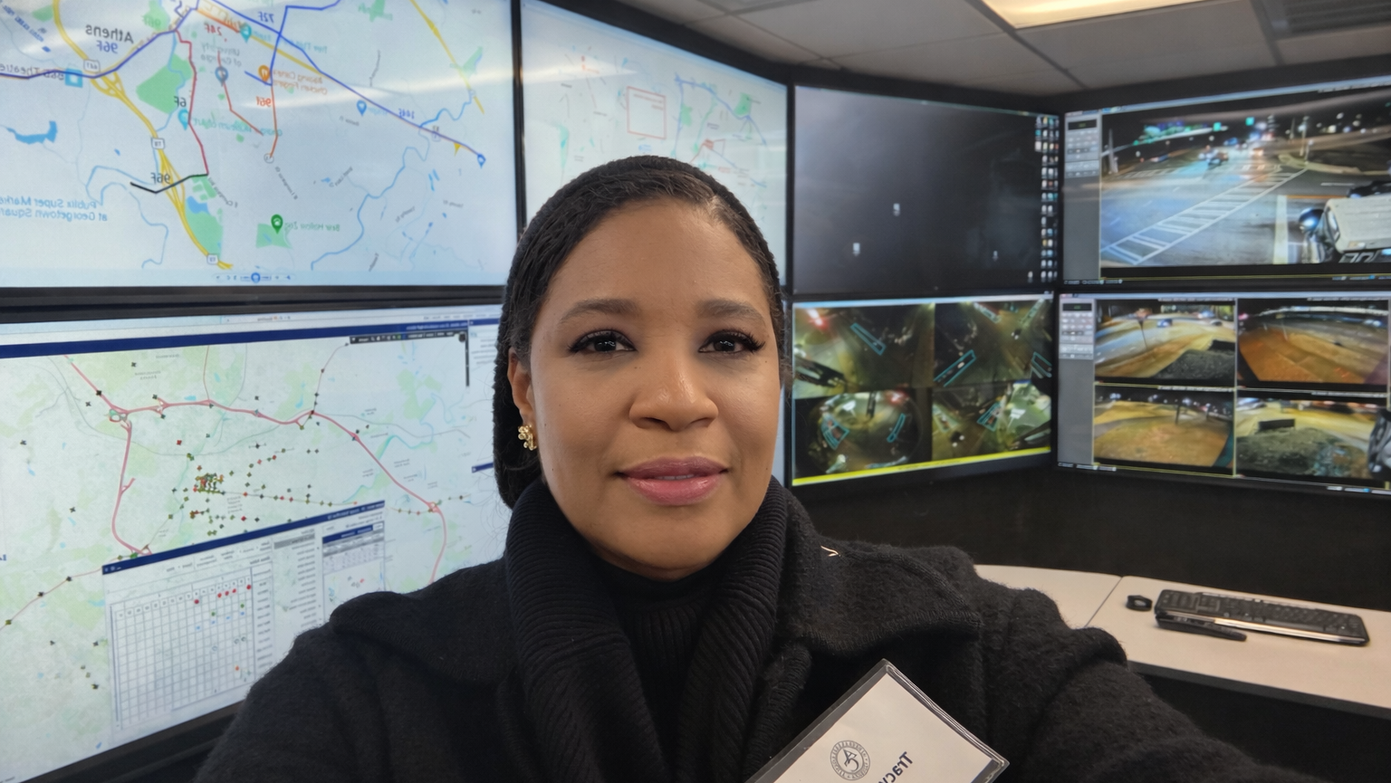 Woman taking a selfie in a control room with multiple screens.