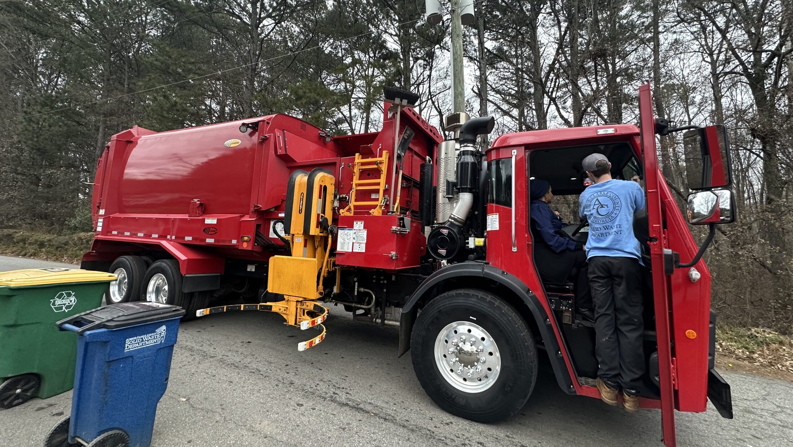 A person inspecting a red fire truck outdoors among trees.