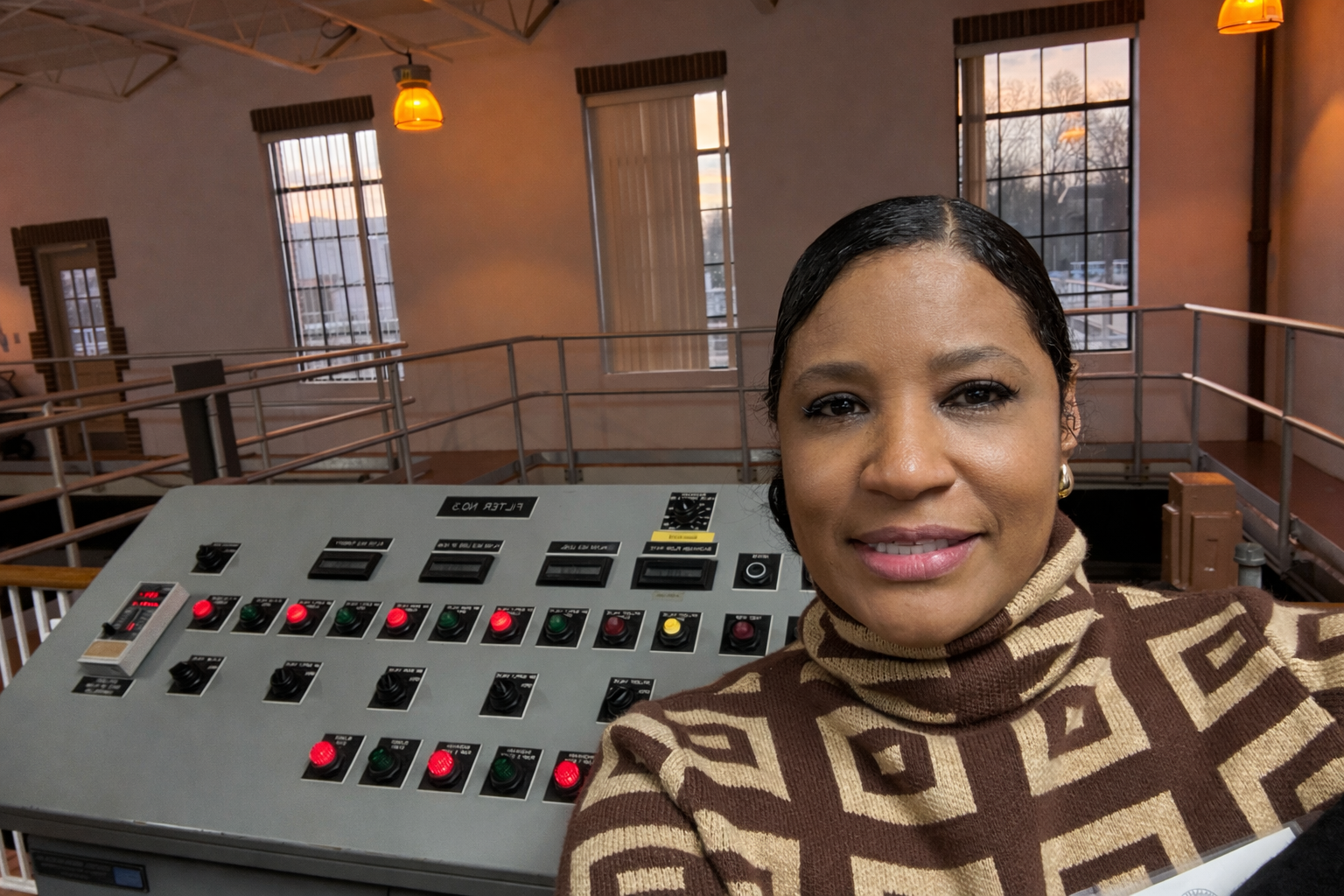 Woman smiling near control panel in an industrial setting.
