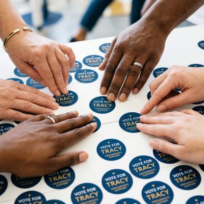 Diverse hands reaching for 'Time to Vote' stickers.